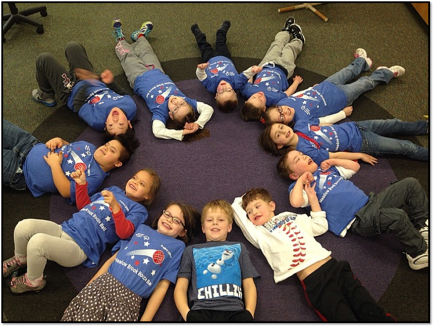 students laying on a carpeted floor in a circular formation